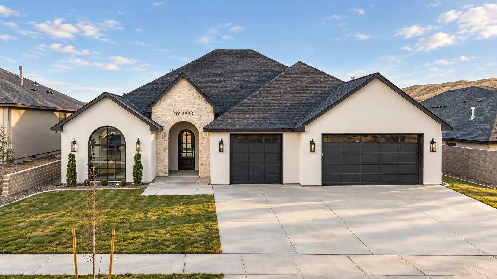 Custom home at 2883 Savanna Avenue with cream stucco, a stone entry, and charcoal garage doors.